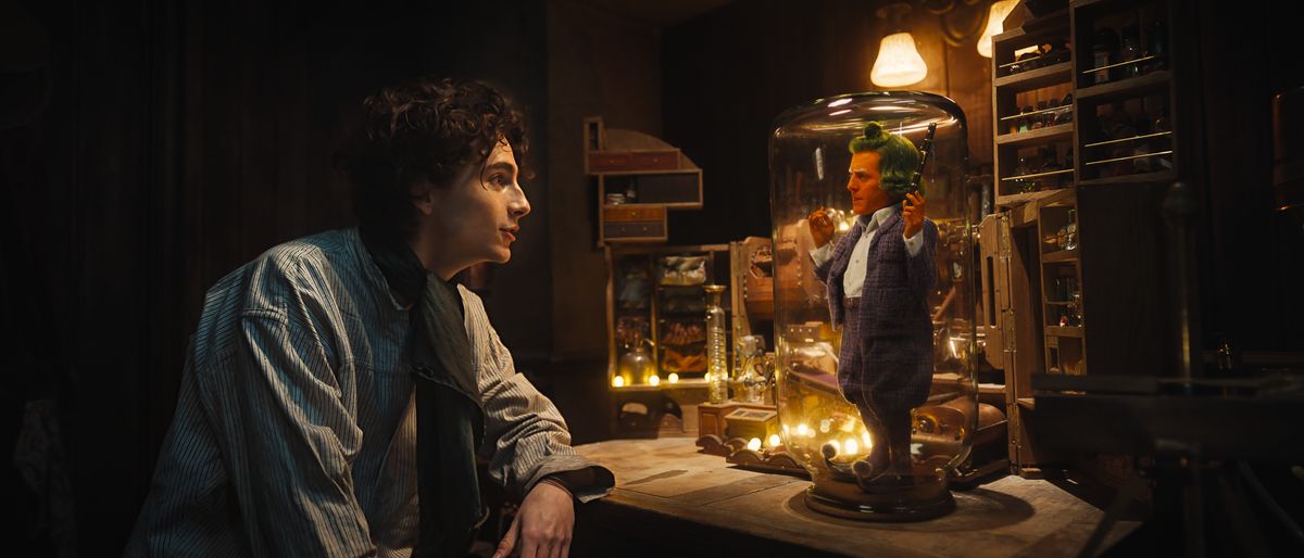 Wonka (Timothée Chalamet) speaking with Lofty the Oompa Loompa (Hugh Grant)