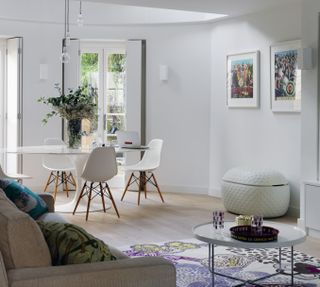 White living room with grey sofa in foreground and white dining set in the background