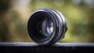 Helios 44-2 lens on a dark surface against a blurry woodland background