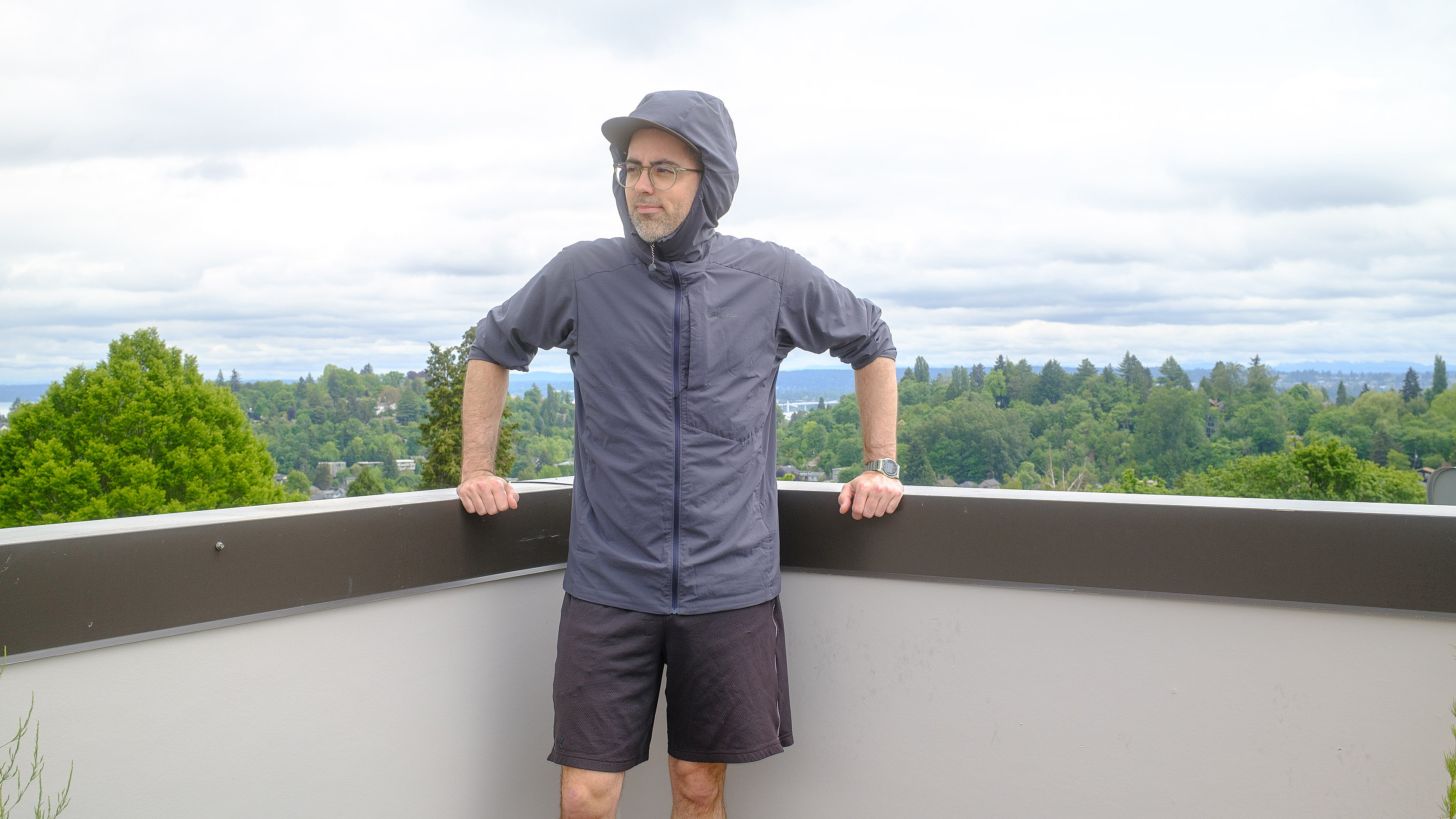 Senior writer Dan Bracaglia wearing the Patagonia Nano-Air Ultralight in grey/blue on the roof of his home in Seattle, Washington with trees and overcast skies in the distance