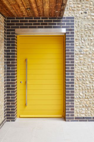 contemporary yellow front door from urban front on the front of a brick house