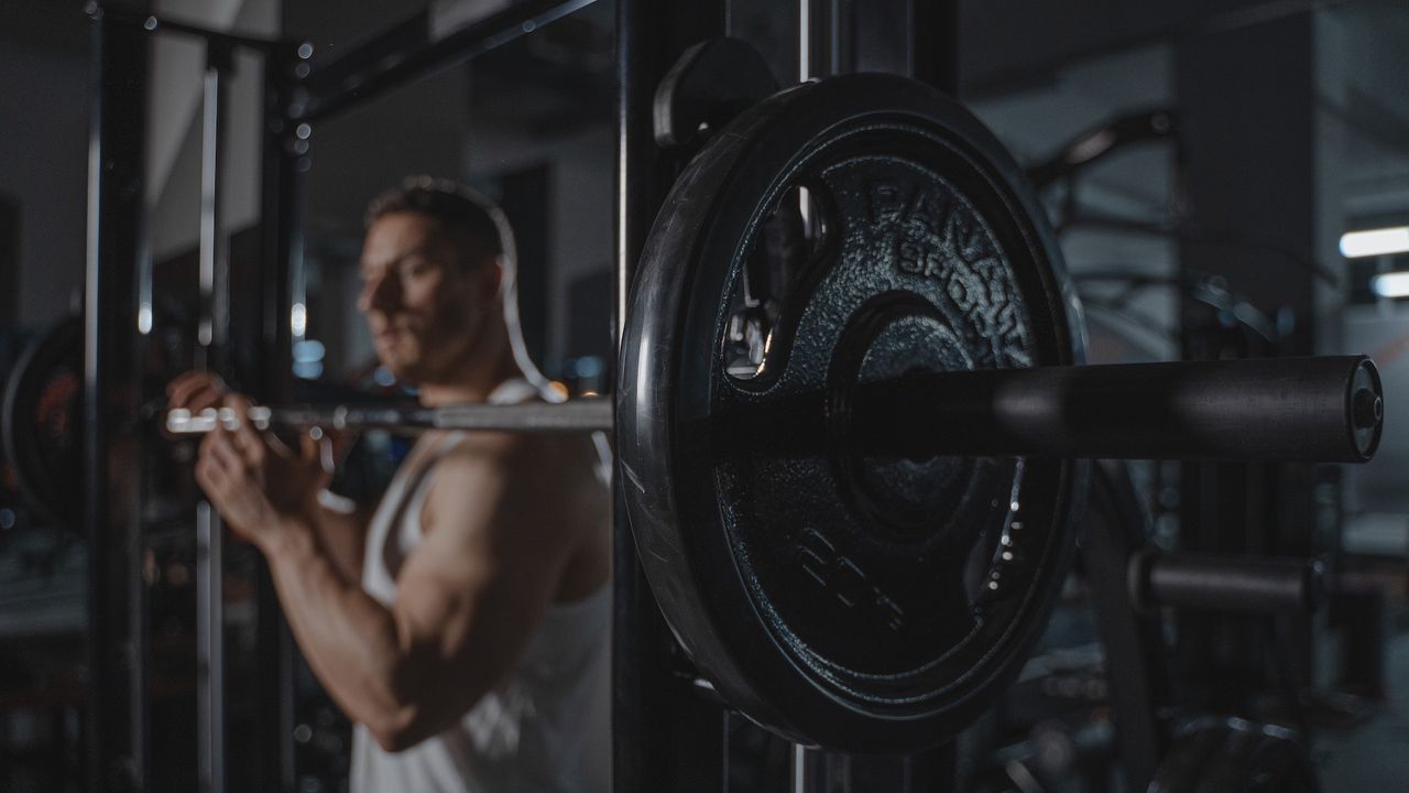 Best squat rack: Pictured here, a bodybuilder secruing the weight plates on a barbell in a gym