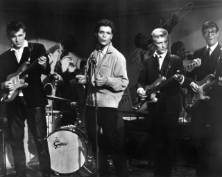 Cliff Richard performing with The Shadows in 'Expresso Bongo', directed by Val Guest, 1959. Left to right: Bruce Welch, Cliff Richard, Jet Harris (1939 - 2011) and Hank Marvin. The drummer, obscured by Richard, is Tony Meehan.