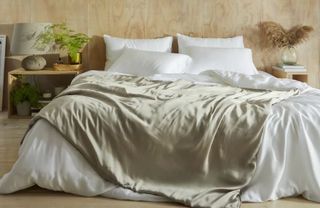 a bed with oatmeal coloured blanke draped over white bedding