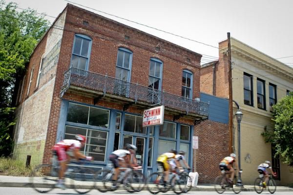 Riders pass an old bike shop along the course