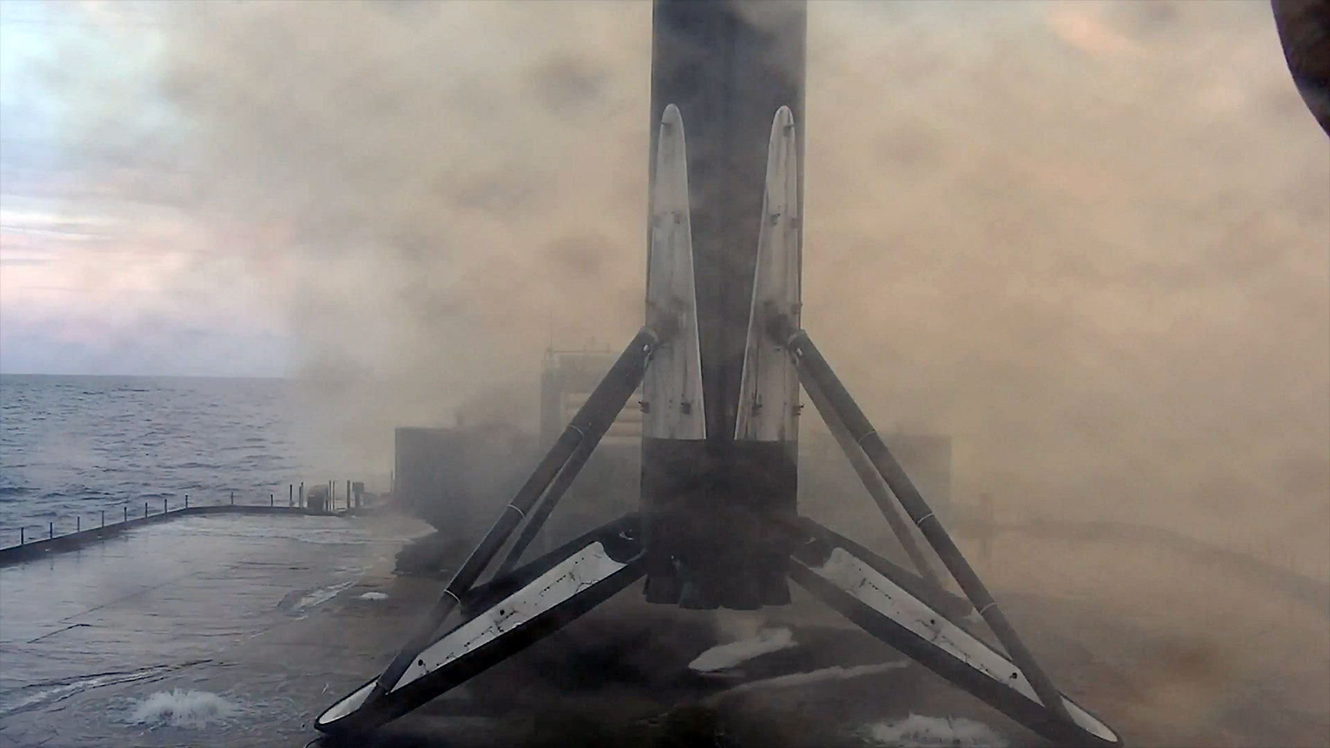 the first stage of an orbital-class rocket stands on its four landing legs atop an ocean-based platform