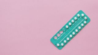 Blue packet of pills on pink background