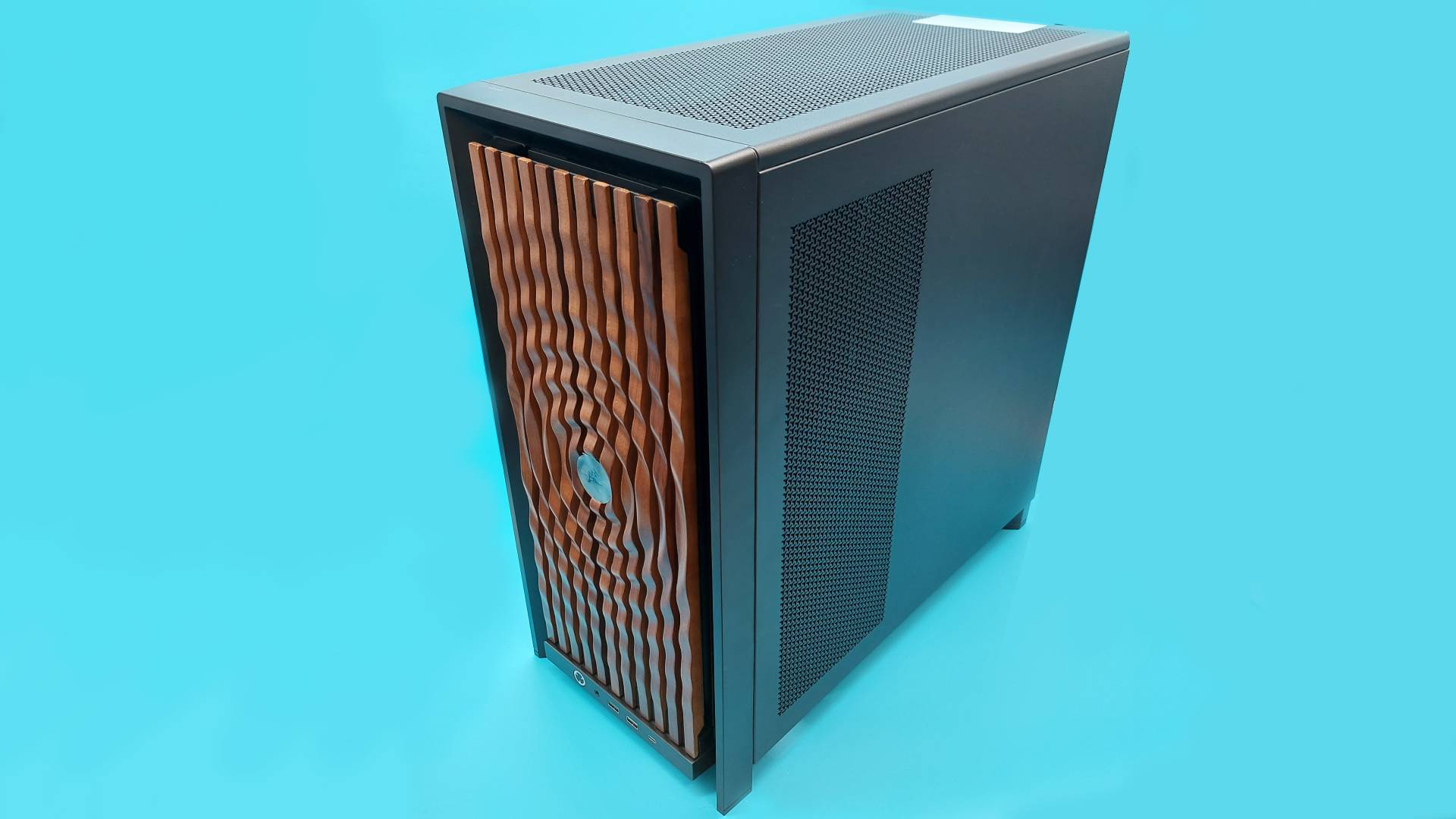 The Corsair Frame 4000X PC case with the rippling wood face plate. It's in a light blue light box, and reflections of the blue surroundings are playing off the carved ridges of the ripple design.