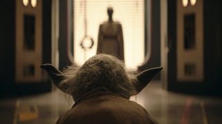 The back of Yoda's long, green pointy ears and wiry white hair fill the screen. The background is blurry, but there is the shape of a tall jedi standing on the other side of the room.