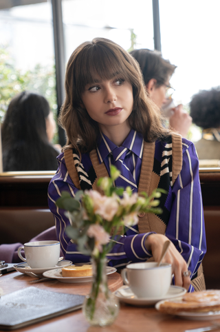 Lily Collins wears a blue striped shirt.