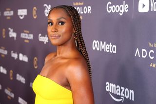 Issa Rae on the red carpet in a yellow dress