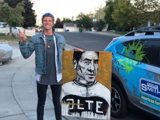 TJ Eisenhart stands with a portrait he painted of cycling legend Eddy Merckx