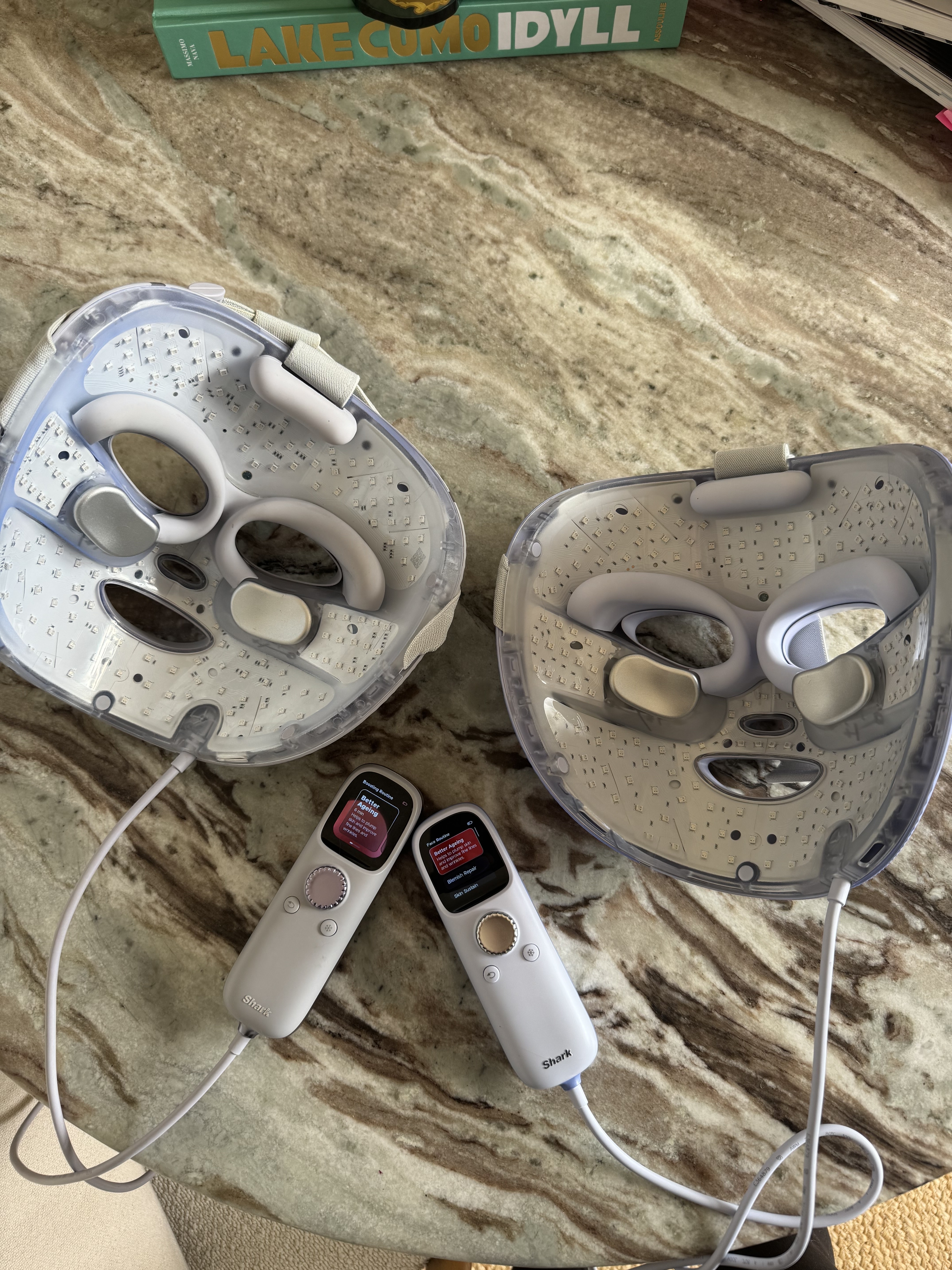 The old Shark CyroGlow LED mask side by side with the new Shark CryoGlow Plus LED mask on a marble dining table