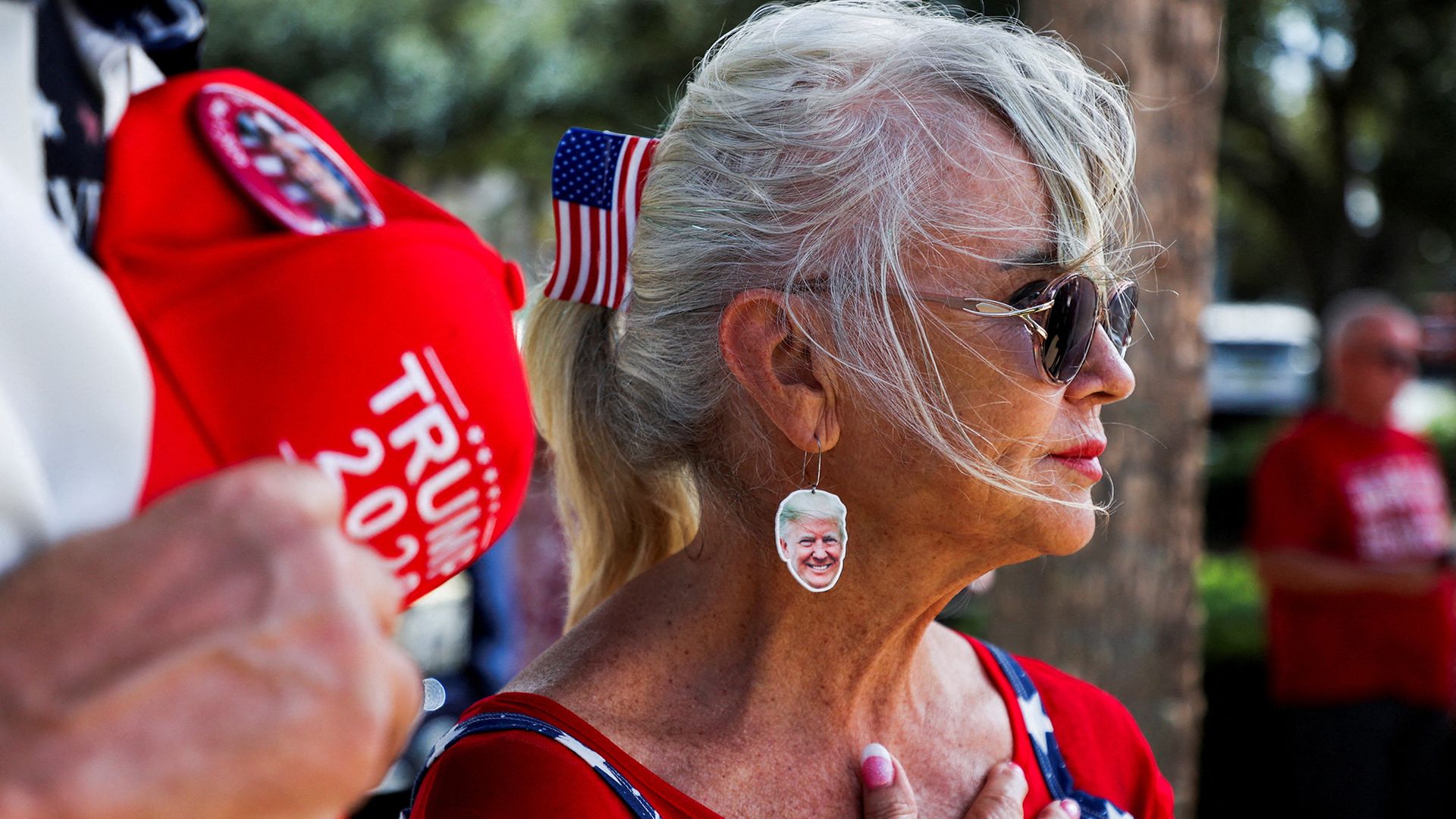 A woman wears earrings depicting US President Donald Trump during a Republican voter turnout event ahead of the midterm elections in The Villages community, Florida