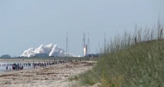 Beachgoers watch a United Launch Alliance Atlas 5 rocket and its classified NROL-33 payload launch into space from Florida's Cape Canaveral Air Force Station on a mission for the U.S. National Reconnaissance Office on May 22, 2014.