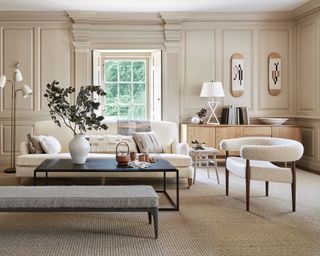 A living room with taupe walls and white contemporary curved sofa and armchairs