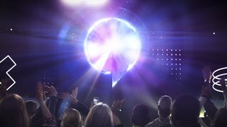 Gamescom 2022 key visual of a purple speech bbubble emitting light over a crowded audience holding phones and waving
