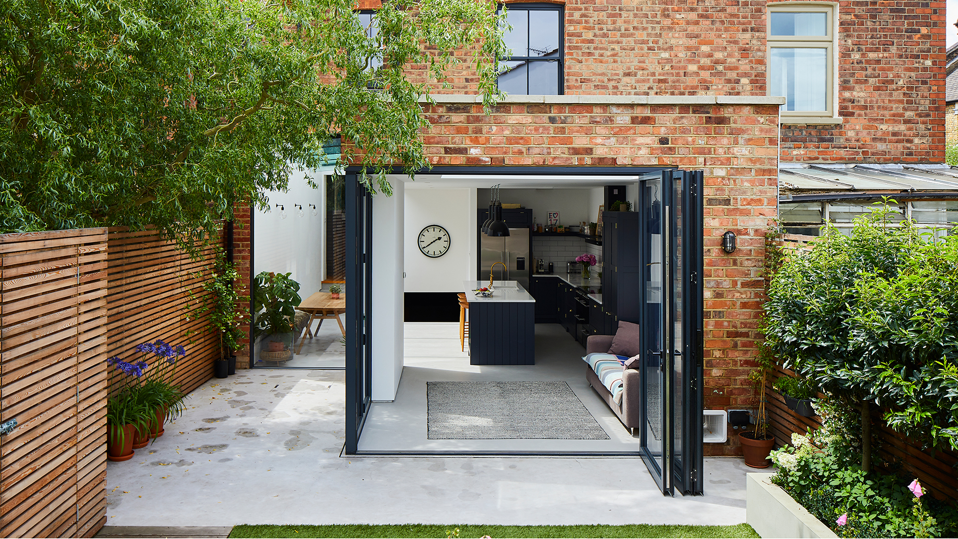 Rear exterior of a brick house with glass doors to open up the extension into the garden