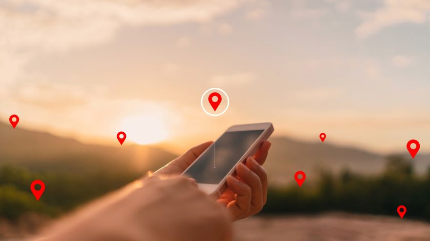 Outdoor photograph of a pair of hands holding a smartphone with navigator location points in the background