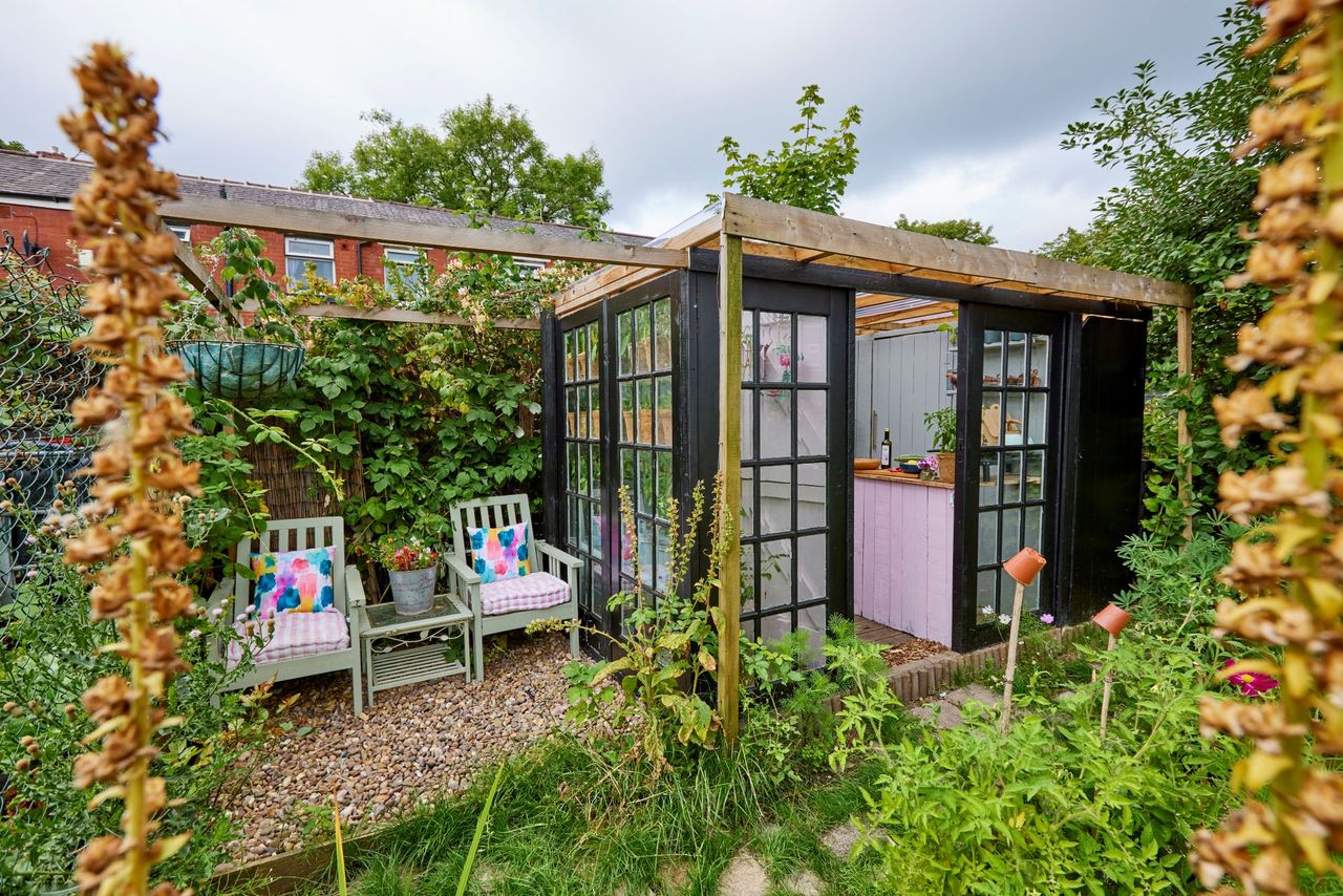 The overall winning shed of the 2022 Curpinol Shed of the Year competition, surrounded by wildflowers , with black painted walls, filled with a variety of plants
