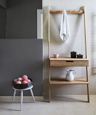 An example of bathroom shelf ideas showing a bathroom with a freestanding wooden shelving unit featuring drawers and towel pegs