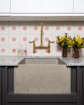 concrete sink with brass taps and pink and white encaustic tiles