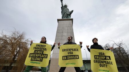 Greenpeace protestors holding yellow signs