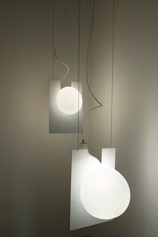 Two white light vases illuminated and hanging down from the ceiling.