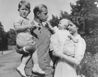 Prince Philip holding Prince Charles and the Queen holding Princess Anne in the grounds of Clarence House