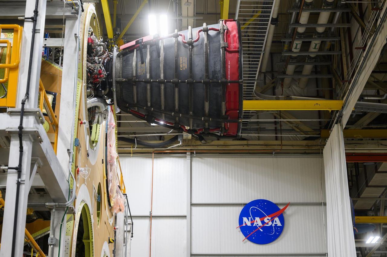 A close-up of the first RS-25 engine that will be used on the Artemis 2 moon mission, on the Space Launch System rocket core stage, with the NASA logo visible on the wall in behind.