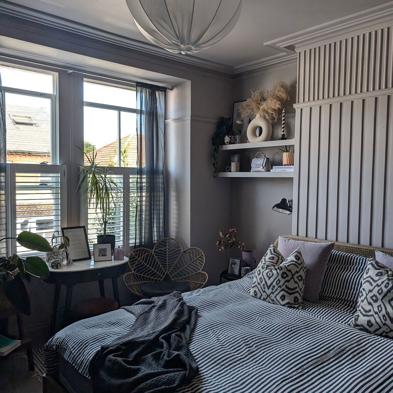 Grey bedroom with wall panelling, monochrome bedding and half blinds on windows