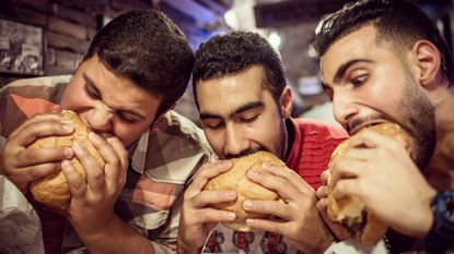 Men eating large burgers