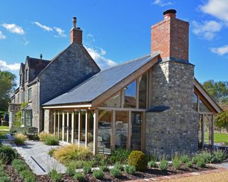 Oak garden room with floor-to-ceiling windows and a brick chimney, in Somerset - designed by David Salisbury