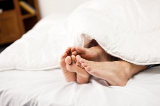 Why do orgasms feel so good? A couple in bed together, shot of their feet