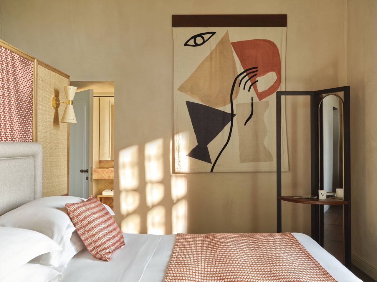 A design hotel with historic, vaulted architectural walls houses a selection of retro-inspired furniture, including colorful sculptural armchairs, layered wallpapers and panels, tiled flooring, eye-catching artworks, and wavy sofas, along with a panoramic rooftop bar with sun loungers.