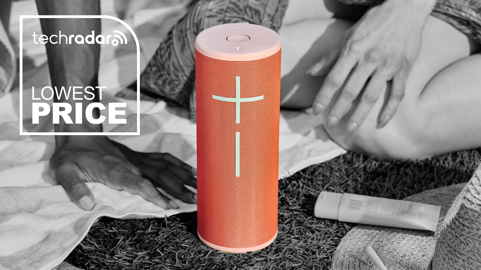 Ultimate Ears Megaboom 4 in a peach colour, standing vertically in the centre of the image. The rest of the image with people sitting around the speaker is black and white.