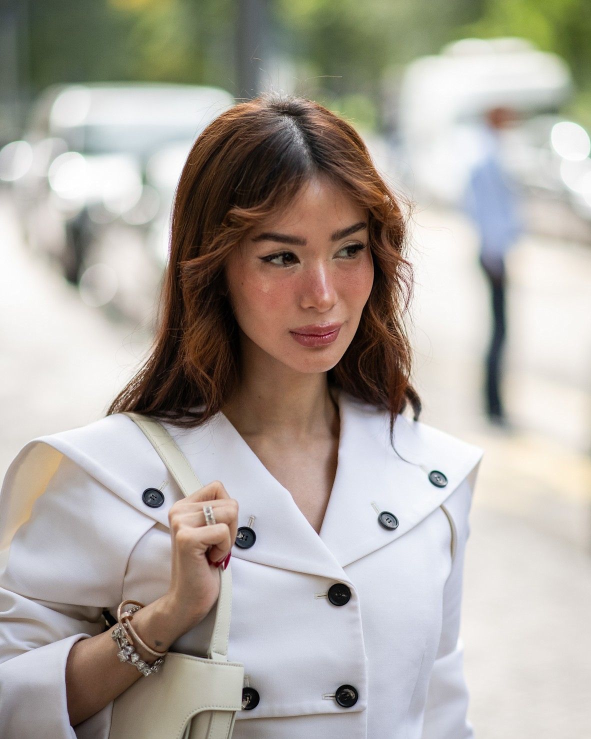 a model with red hair and brown roots in a white blazer  poses for a portrait.