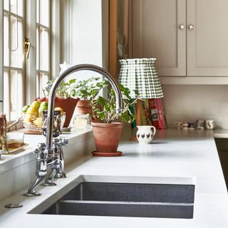 Stainless steel kitchen sink under window with white countertops