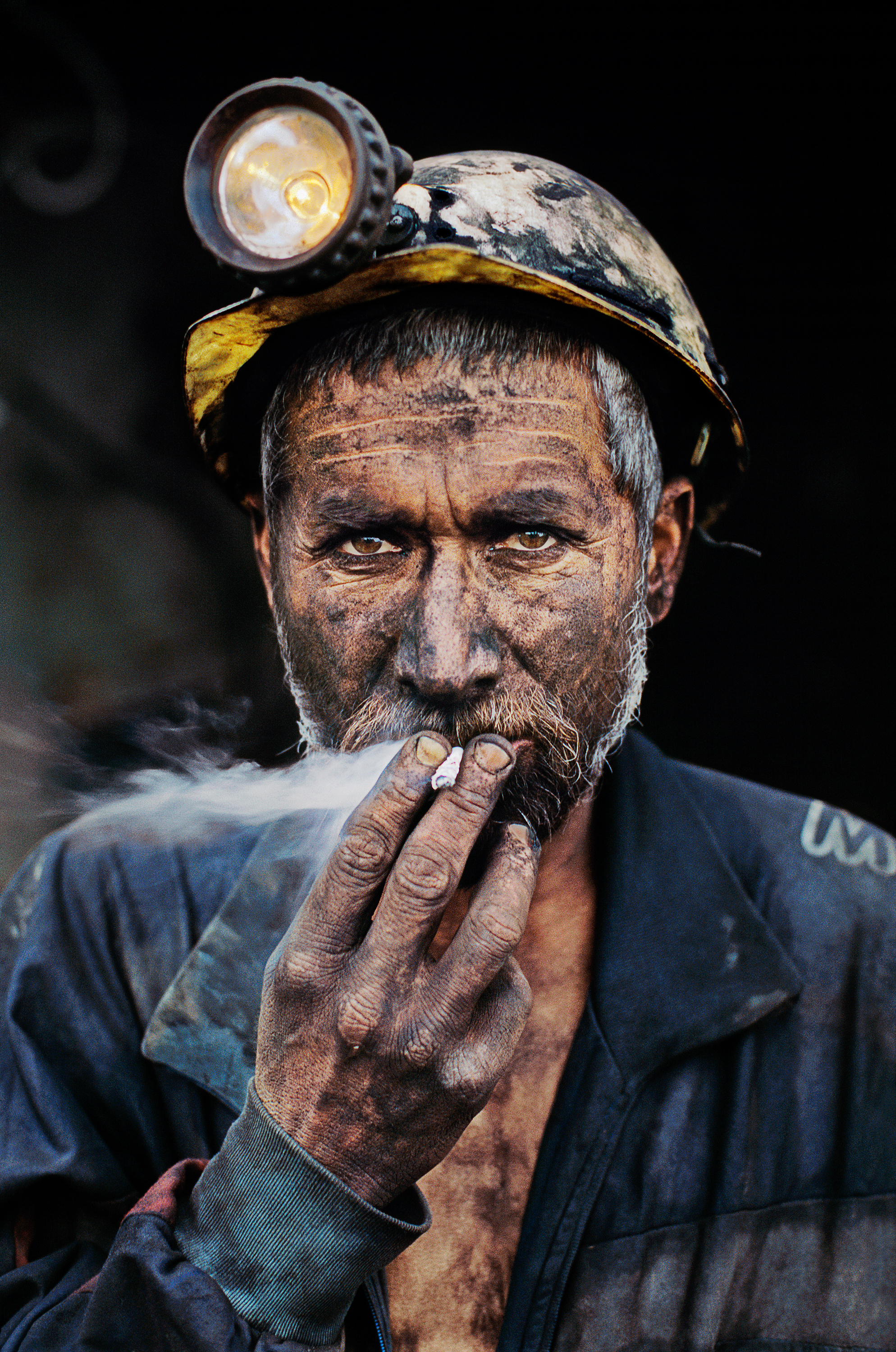 Pol-e-Khomri, Afghanistan, 2002. A coal miner, dark with the dust from the mine, smoking a cigarette.