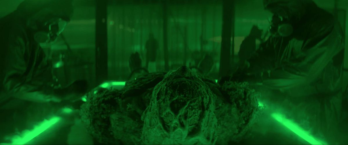 Swamp Thing lays on a dissection table surrounded by masked men