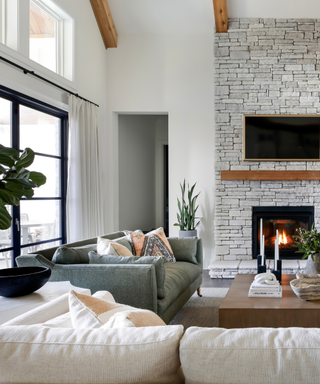 A beige-toned living room with a green couch and a fireplace.