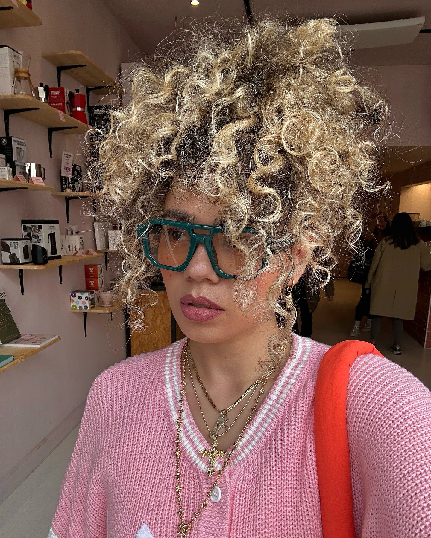 Uma mulher com cabelo encaracolado estilizado em um penteado, com raízes naturais e extremidades loiras brilhantes