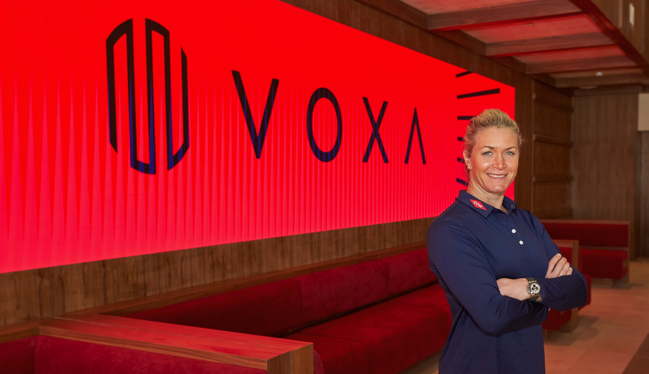 Suzann Pettersen poses in front of a VOXA board