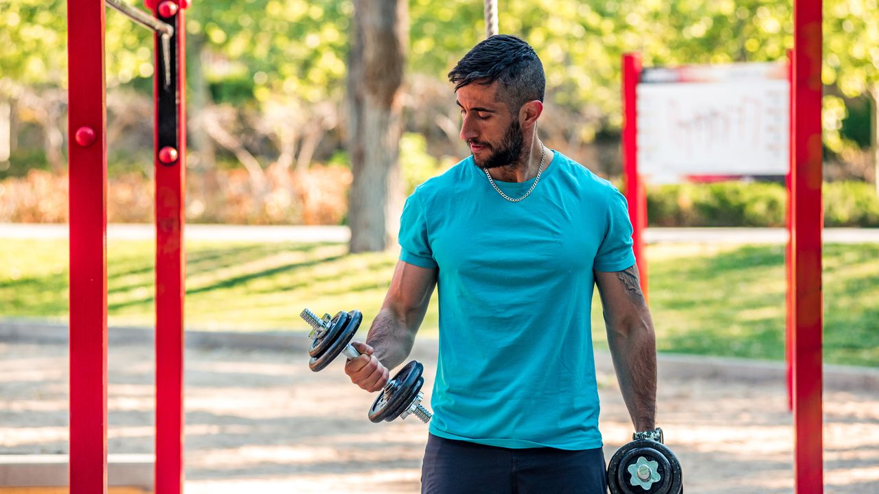 Man doing dumbbell curls outside