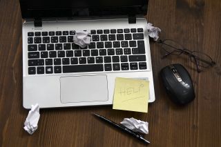 A laptop with crumpled notes and a request for help.