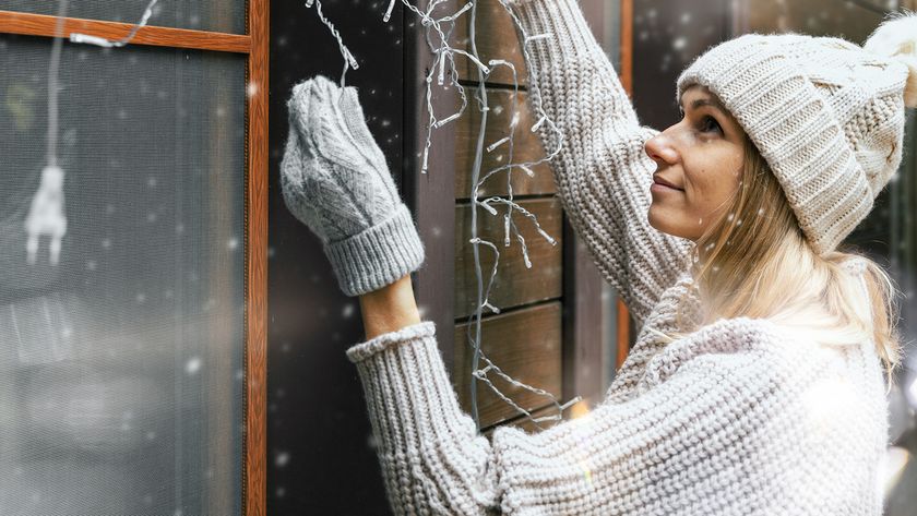 Woman decorating house with christmas lights outdoors