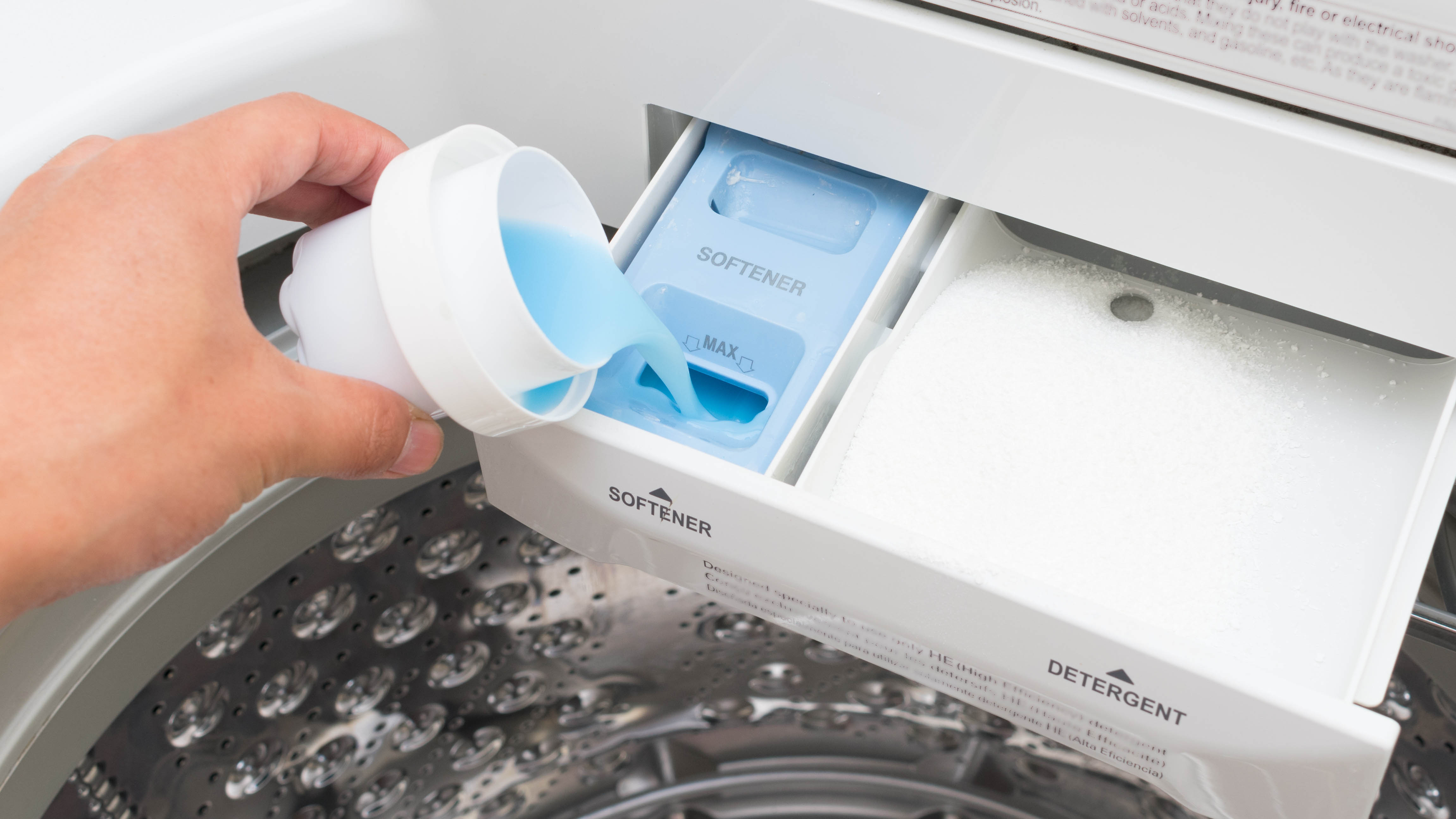 Someone pouring detergent into a detergent drawer on a front load washer