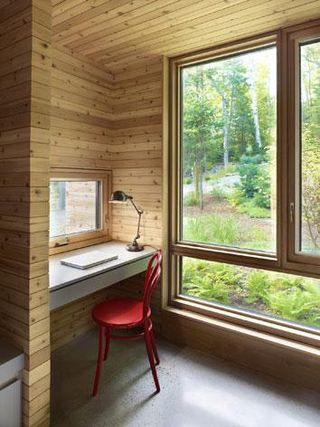 Large wood-framed openings face the forested landscape