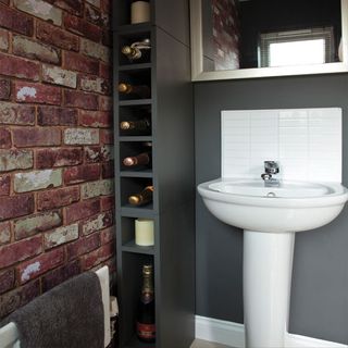 bathroom basin in grey room with brick effect wallpaper
