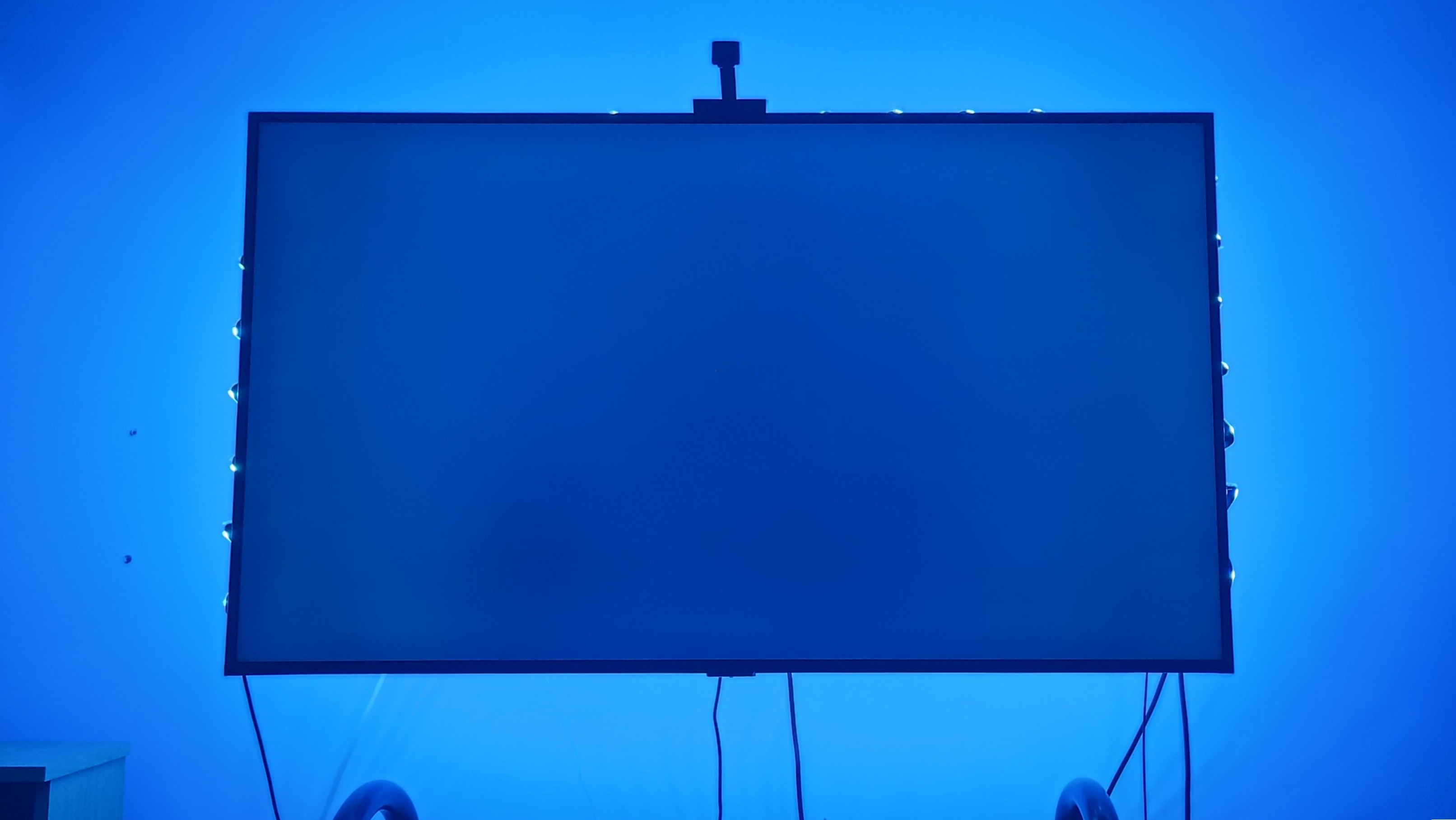 A TV with a blue screen with an LED lightstrip emitting blue light 
